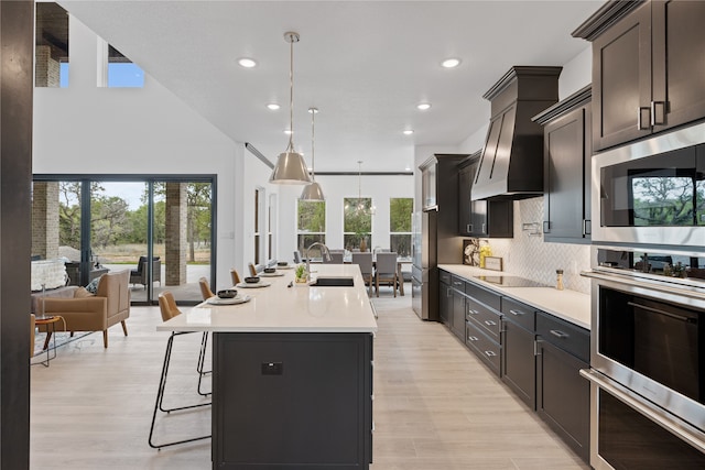 kitchen featuring sink, hanging light fixtures, plenty of natural light, an island with sink, and ventilation hood