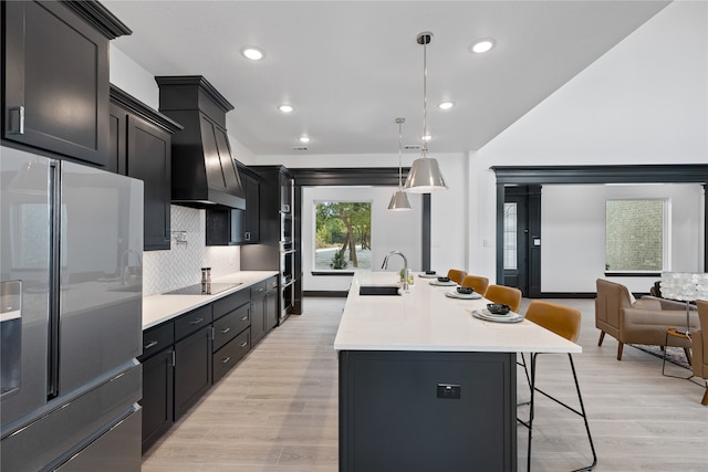 kitchen featuring decorative light fixtures, tasteful backsplash, light wood-type flooring, and a kitchen bar