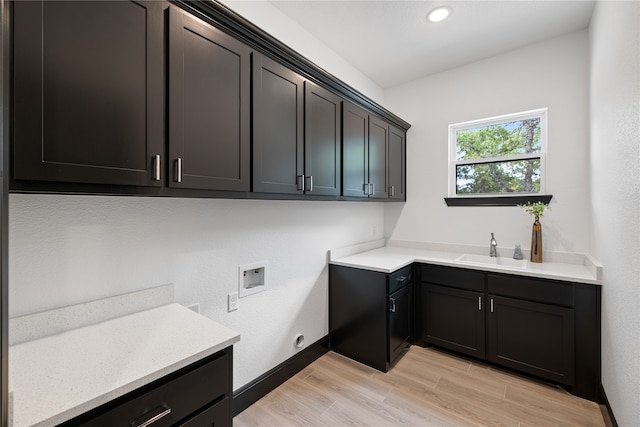 laundry area featuring hookup for a washing machine, light hardwood / wood-style floors, sink, and cabinets