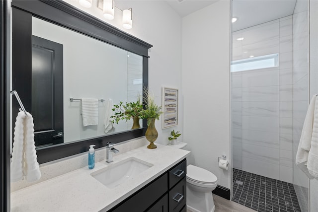 bathroom featuring tiled shower, vanity, and toilet