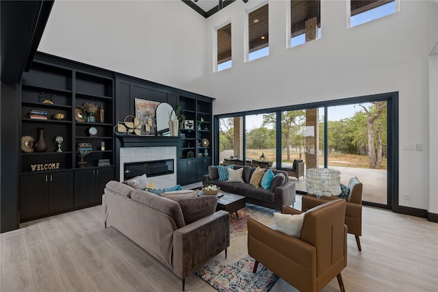 living room featuring a towering ceiling, built in features, and light wood-type flooring