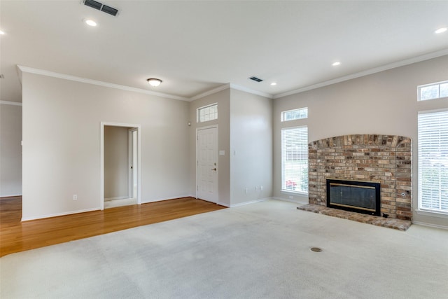 unfurnished living room with light colored carpet, a fireplace, ornamental molding, and a healthy amount of sunlight