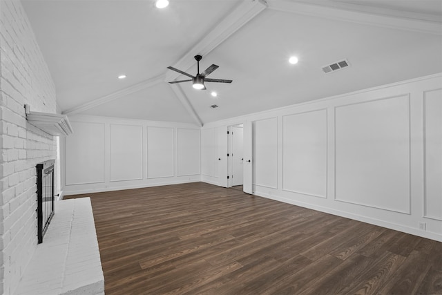 unfurnished living room featuring dark wood-type flooring, ceiling fan, beamed ceiling, a brick fireplace, and brick wall