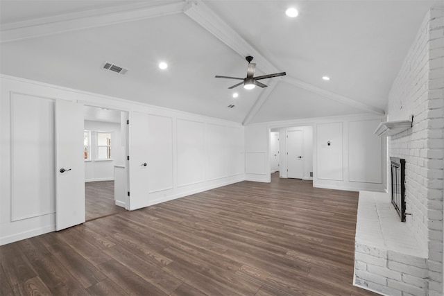 unfurnished living room featuring beam ceiling, dark wood-type flooring, ceiling fan, a brick fireplace, and brick wall