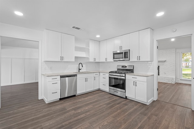 kitchen with dark hardwood / wood-style floors, stainless steel appliances, backsplash, and white cabinets