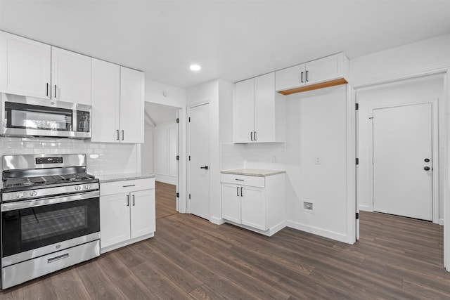 kitchen featuring appliances with stainless steel finishes, white cabinets, backsplash, light stone countertops, and dark hardwood / wood-style flooring