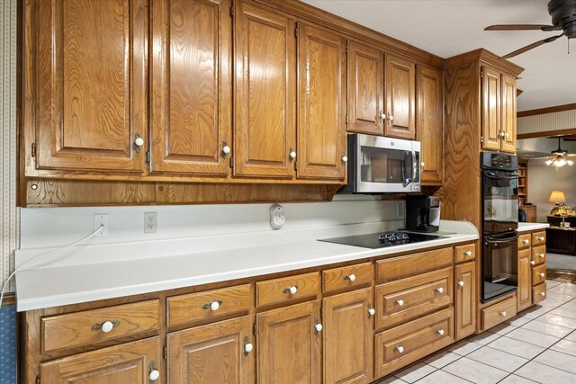 kitchen with ceiling fan, black appliances, ornamental molding, and light tile patterned floors