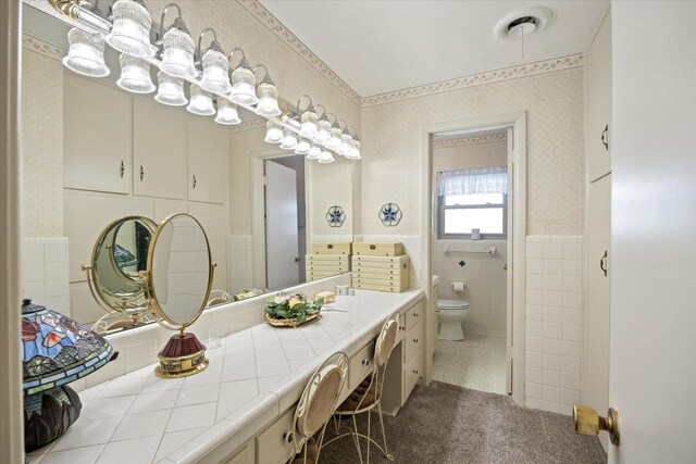 bathroom with vanity, toilet, tile walls, and tile patterned flooring