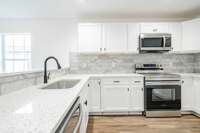 kitchen featuring sink, stainless steel appliances, light stone counters, white cabinets, and decorative backsplash