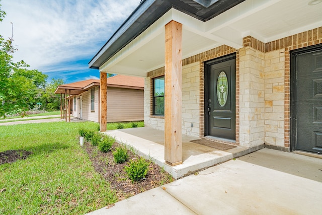 entrance to property with covered porch and a yard