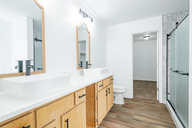 bathroom with wood-type flooring, vanity, an enclosed shower, and toilet