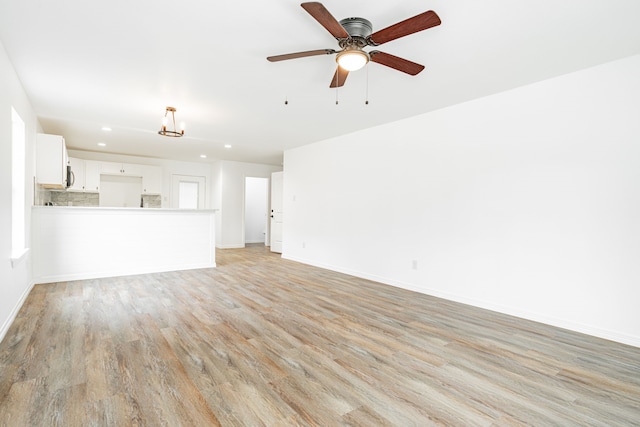 unfurnished living room featuring ceiling fan and light hardwood / wood-style flooring