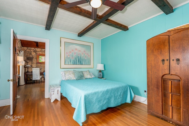 bedroom with beam ceiling, hardwood / wood-style flooring, ornamental molding, and ceiling fan