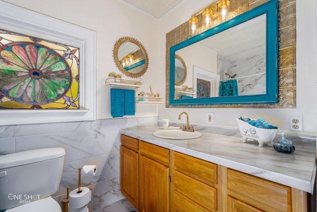 bathroom with vanity, tile walls, toilet, a textured ceiling, and tile patterned flooring