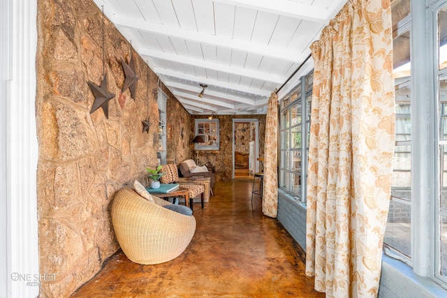 hall with lofted ceiling with beams, wooden ceiling, and concrete floors