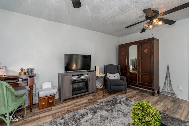 living room featuring wood-type flooring, a textured ceiling, and ceiling fan