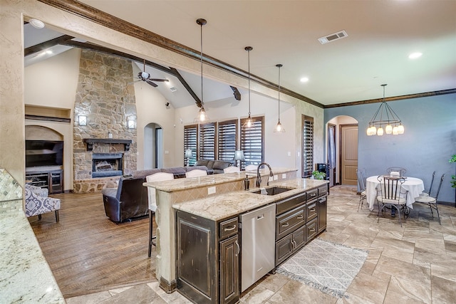 kitchen featuring a kitchen bar, hanging light fixtures, sink, and stainless steel dishwasher