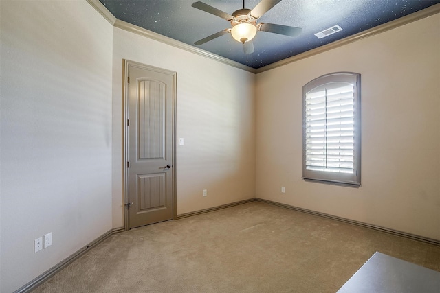 empty room featuring ceiling fan, crown molding, light colored carpet, and a textured ceiling