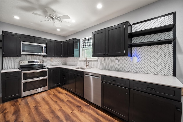 kitchen featuring wood-type flooring, tasteful backsplash, ceiling fan, sink, and appliances with stainless steel finishes