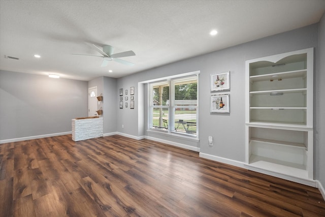 unfurnished living room with ceiling fan, a textured ceiling, hardwood / wood-style flooring, and built in shelves