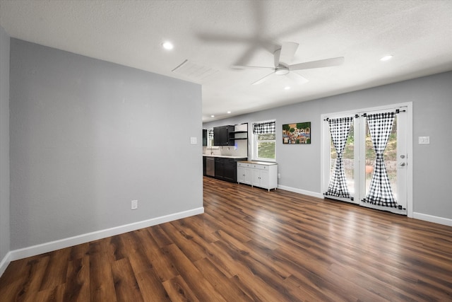 unfurnished living room with a textured ceiling, ceiling fan, and dark wood-type flooring