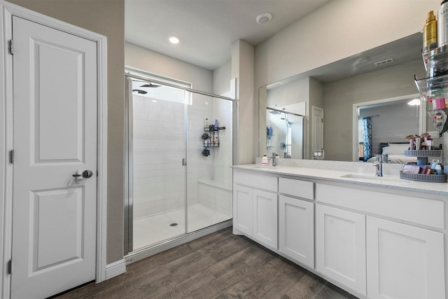 bathroom featuring hardwood / wood-style floors, vanity, and a shower with shower door