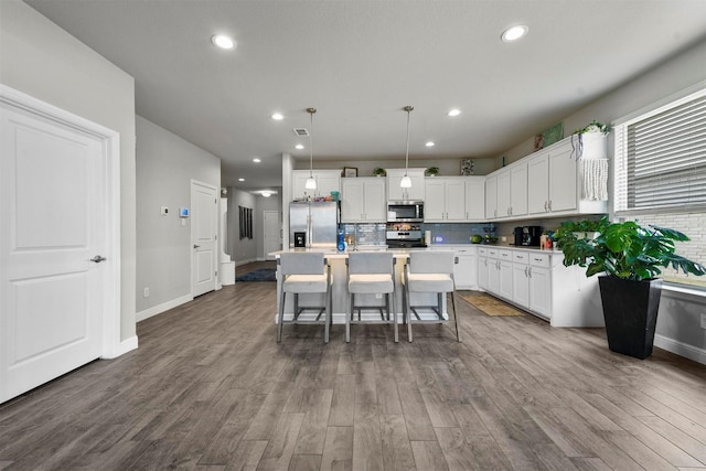 kitchen featuring appliances with stainless steel finishes, a kitchen breakfast bar, a center island, white cabinetry, and hanging light fixtures