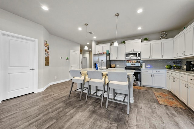 kitchen with stainless steel appliances, dark hardwood / wood-style flooring, an island with sink, decorative light fixtures, and white cabinets