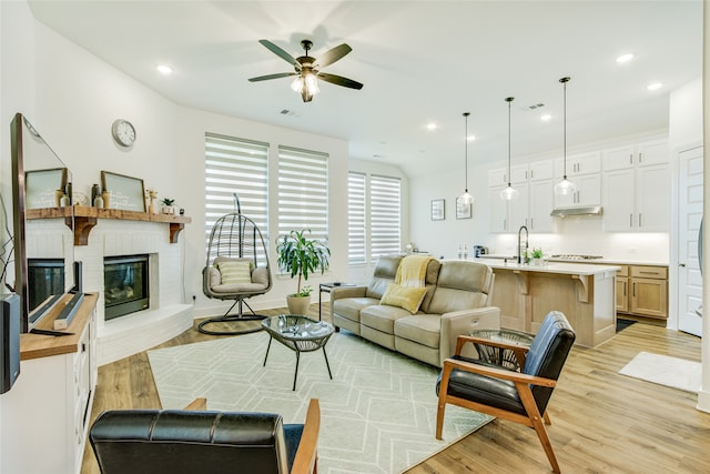 living room with light hardwood / wood-style flooring, a fireplace, and ceiling fan