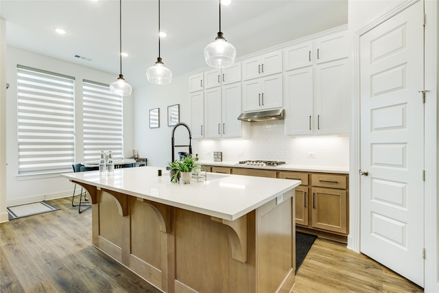 kitchen featuring white cabinetry, an island with sink, and light hardwood / wood-style flooring