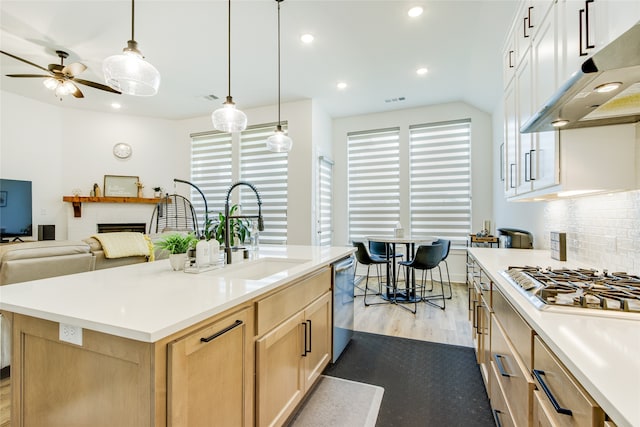 kitchen featuring white cabinets, sink, light hardwood / wood-style floors, decorative backsplash, and a kitchen island with sink