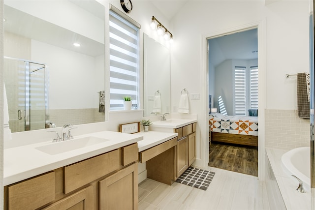 bathroom featuring dual vanity, separate shower and tub, tile patterned flooring, and vaulted ceiling