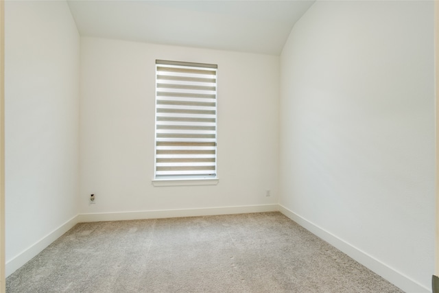 spare room with lofted ceiling, a healthy amount of sunlight, and light colored carpet