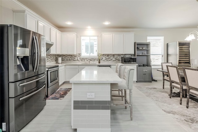 kitchen with a breakfast bar, open shelves, stainless steel appliances, tasteful backsplash, and white cabinetry