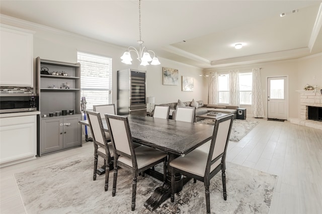 dining area with ornamental molding, an inviting chandelier, a wealth of natural light, and a tray ceiling