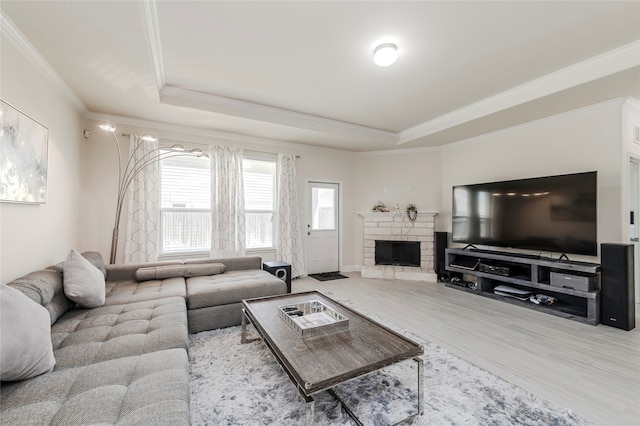 living room with wood-type flooring, a fireplace, crown molding, and a tray ceiling