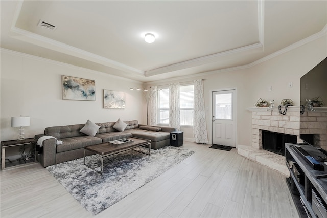 living room featuring ornamental molding, a raised ceiling, and light hardwood / wood-style floors