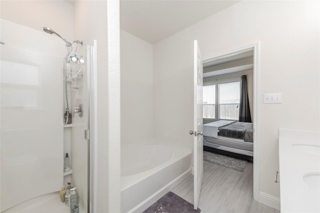 bathroom featuring a tub to relax in, double vanity, connected bathroom, a shower stall, and wood finished floors