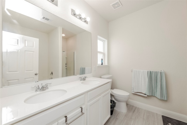 bathroom with dual vanity, hardwood / wood-style flooring, and toilet