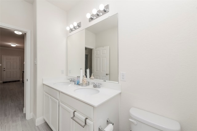 bathroom featuring double vanity, wood-type flooring, and toilet