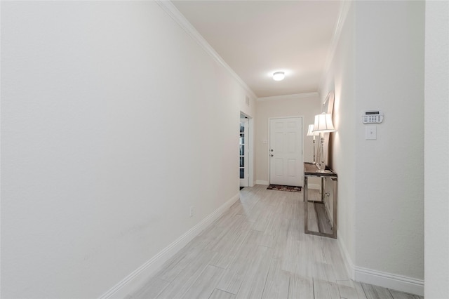 corridor featuring crown molding, light wood-style flooring, and baseboards