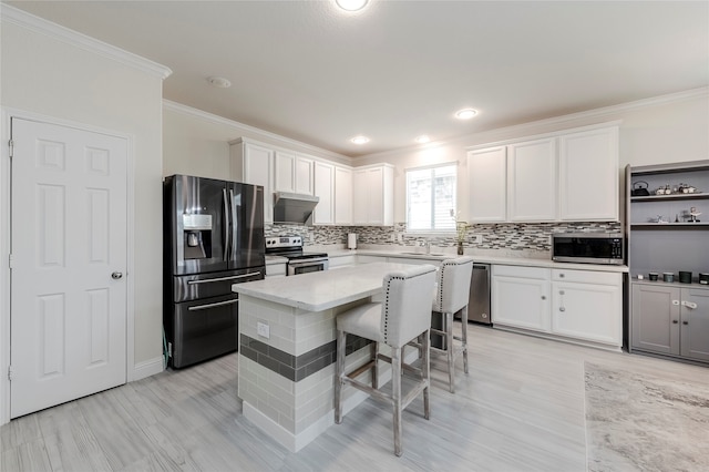 kitchen featuring appliances with stainless steel finishes, white cabinetry, backsplash, and wall chimney exhaust hood