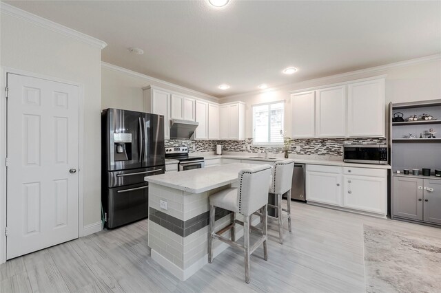 kitchen with white cabinets, extractor fan, stainless steel appliances, and a kitchen breakfast bar