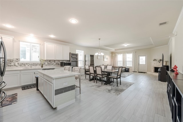 kitchen with ornamental molding, decorative light fixtures, white cabinets, and a kitchen island