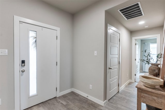 foyer featuring light wood-type flooring, baseboards, and visible vents