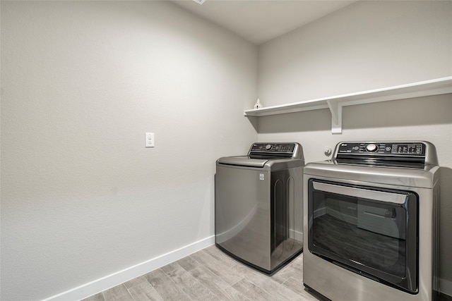 laundry room with washer and clothes dryer and light hardwood / wood-style flooring