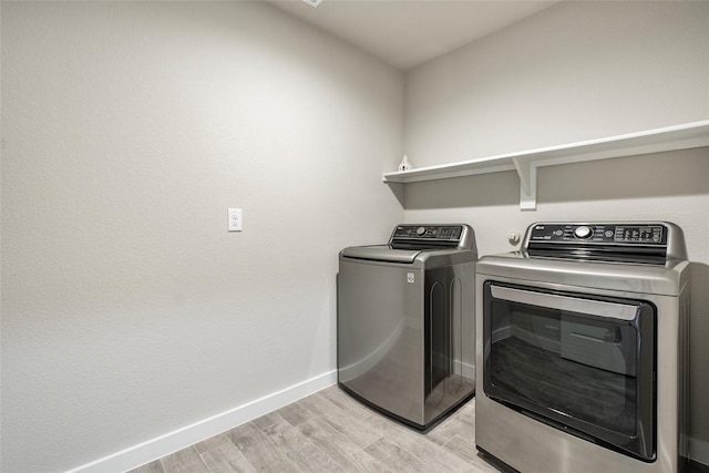 laundry area with light wood-type flooring, laundry area, baseboards, and washer and clothes dryer