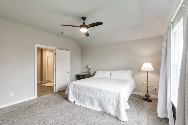 carpeted bedroom with ensuite bath, ceiling fan, and vaulted ceiling