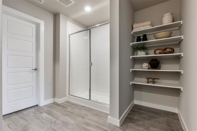 bathroom with a shower with shower door and hardwood / wood-style floors