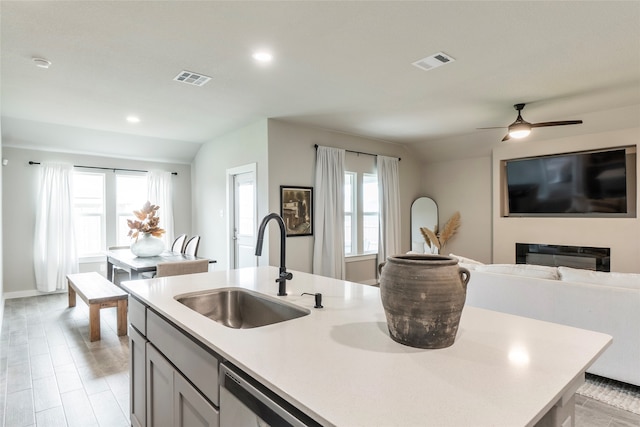 kitchen with sink, a wealth of natural light, ceiling fan, and a center island with sink